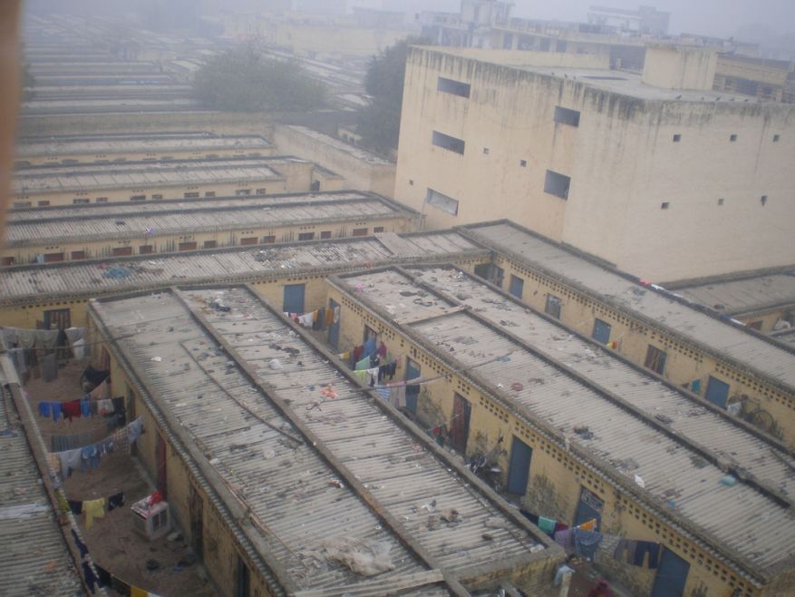 The Kapashera slum is divided into several compounds with rows of tiny ten-by-ten-foot one-room units. Each compound contains thirty to one hundred rooms. Photo: https://gurgaonworkersnews.files.wordpress.com/.