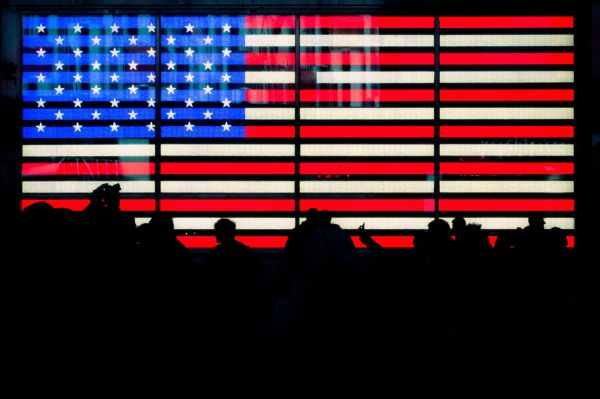 American flag with silhouettes of people in the foreground.